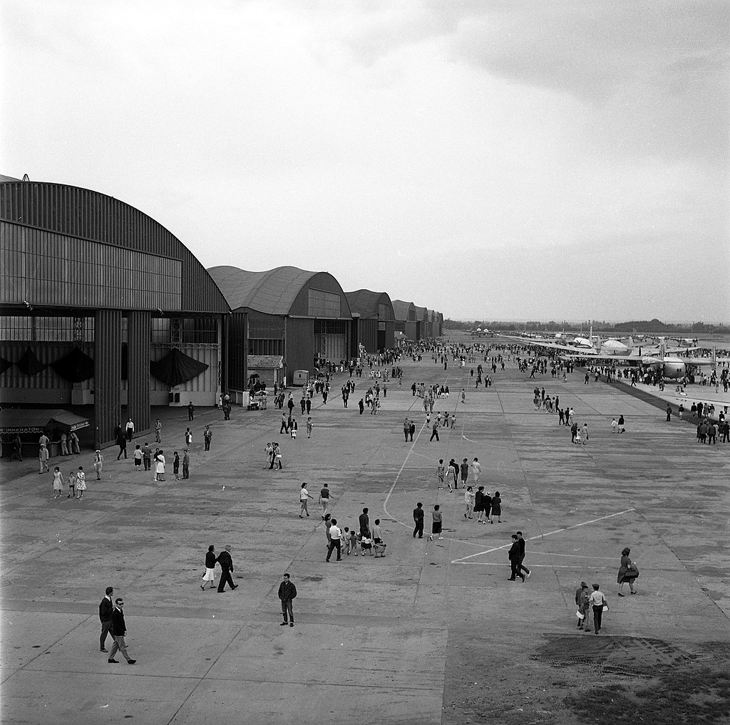L'image montre les portes ouvertes de Francazal en 1963 : on voit des hautes halles à gauche de l'image en noir et blanc, avec des personnes marchant sur la base aérienne