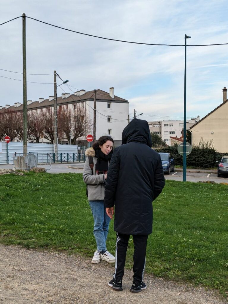 L'image montre 2 personnes debout dans un parc en train de discuter