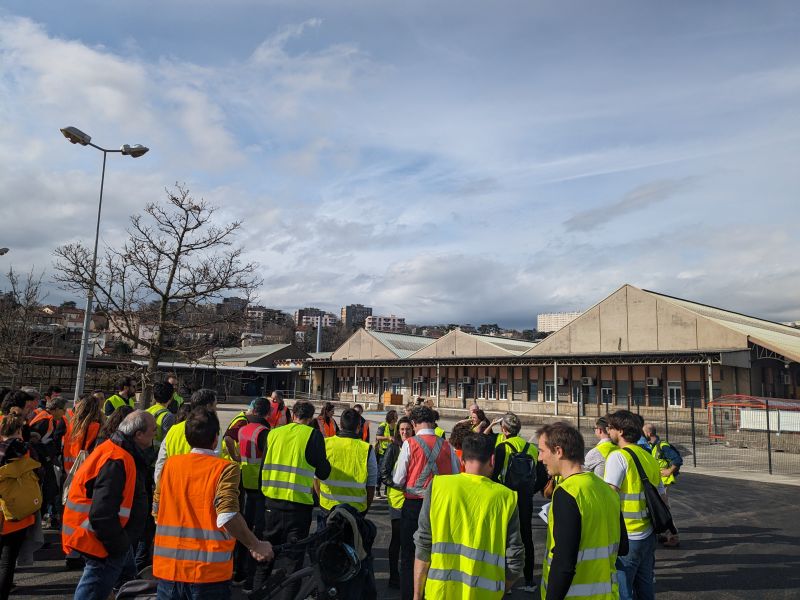 L'image montre un groupe de personnes debout dehors en gilet fluorescent lors de la visite du site
