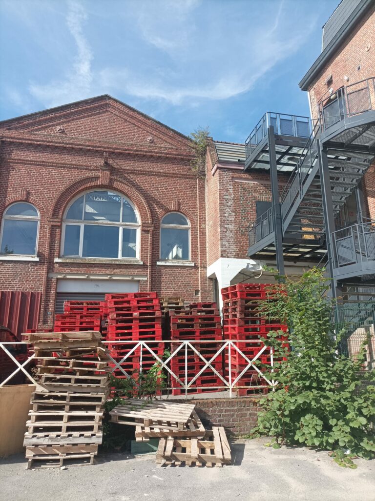 L'image montre un bâtiment en brique, avec une belle verrière: c'est la plateforme de réemploi