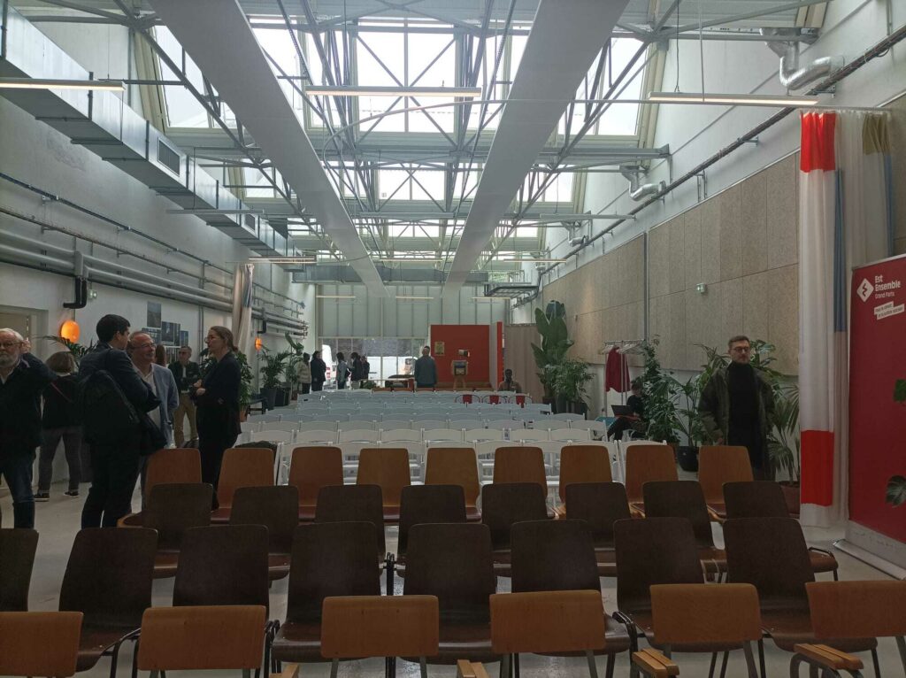L'image montre une salle en longueur avec des chaises en bois au premier plan